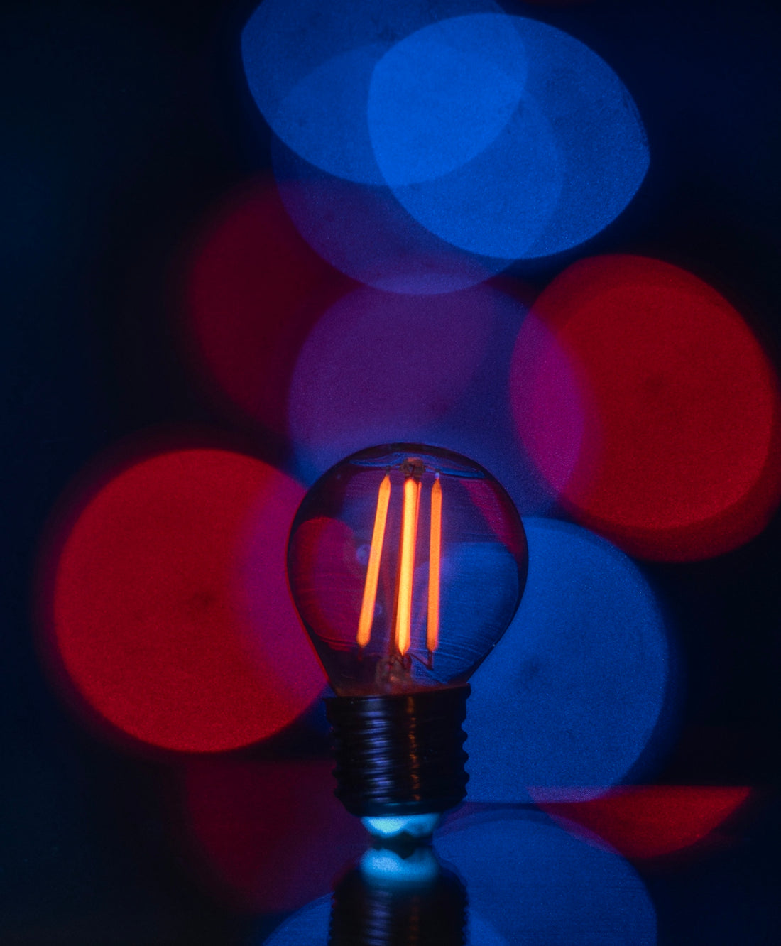 A glowing edison bulb with red and blue bokeh lights.