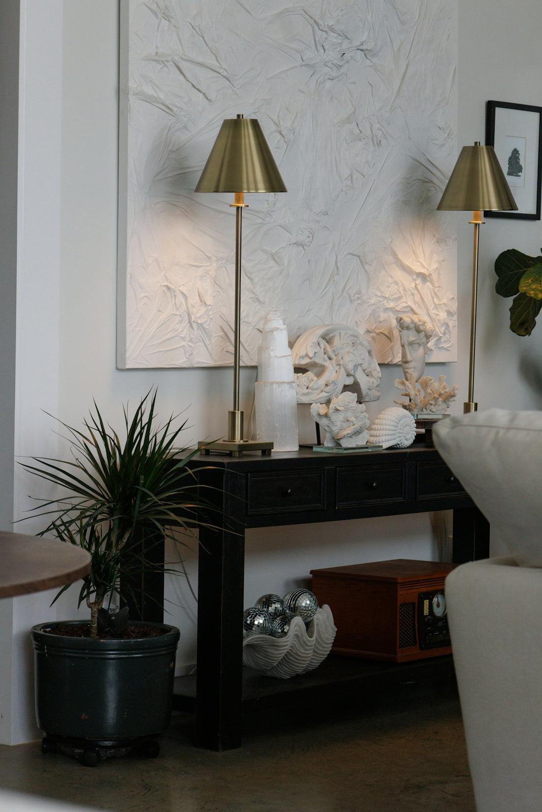 Two brass lamps on a black console table.