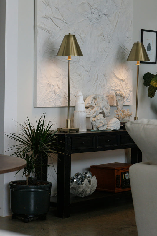 Two brass lamps on a black console table.